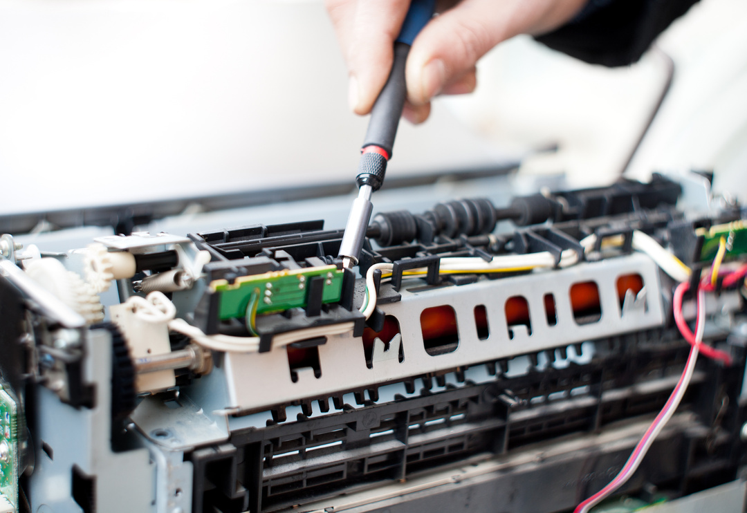 Technician repairing a laser printer with tools